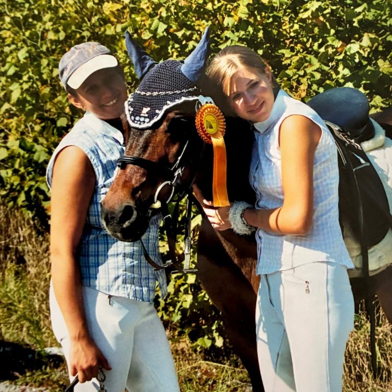 Pony und zwei Menschen mit Schleife auf dem Turnier